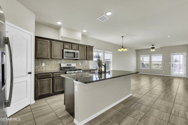 kitchen featuring visible vents, stainless steel appliances, decorative backsplash, dark brown cabinets, and ceiling fan with notable chandelier