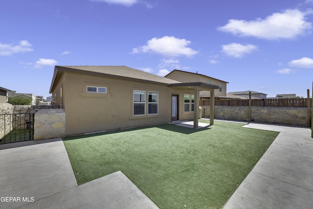 rear view of house with a yard, stucco siding, a patio, and fence