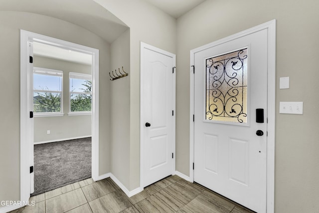 foyer entrance with light colored carpet and baseboards