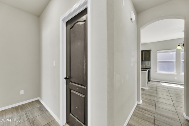 corridor with baseboards and arched walkways