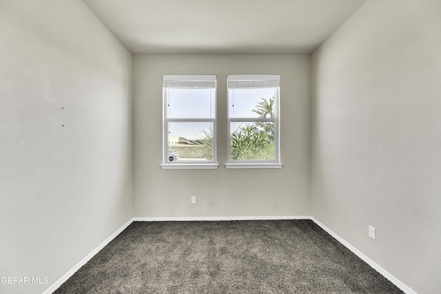 carpeted empty room featuring baseboards