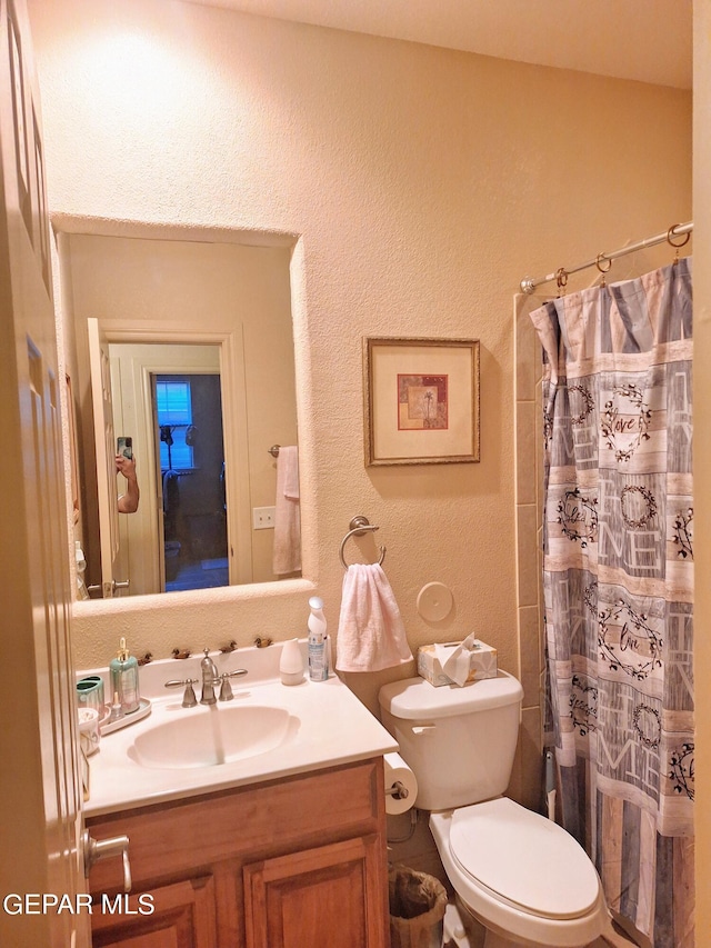 bathroom featuring vanity, curtained shower, and toilet