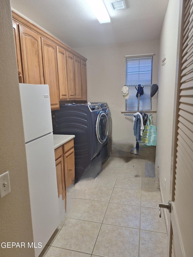 washroom featuring light tile patterned flooring, a textured ceiling, and cabinets