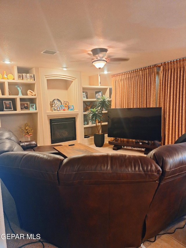 living room with a textured ceiling, built in features, and ceiling fan