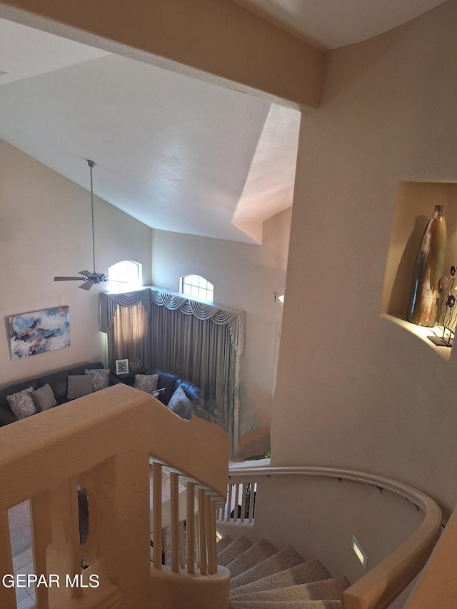 stairway featuring lofted ceiling and ceiling fan