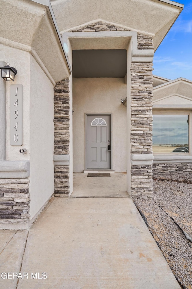 entrance to property featuring stucco siding and stone siding