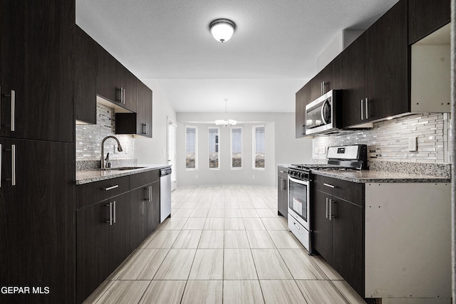 kitchen featuring a sink, decorative backsplash, stainless steel appliances, a textured ceiling, and a chandelier