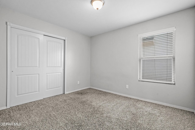 unfurnished bedroom with a closet, baseboards, and carpet flooring