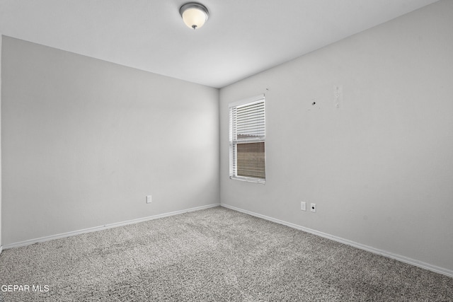 carpeted spare room featuring baseboards