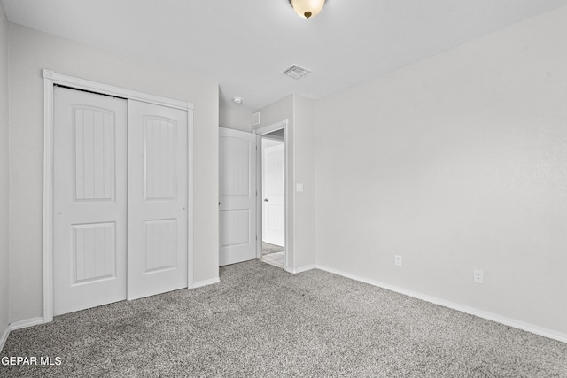 unfurnished bedroom with a closet, baseboards, visible vents, and carpet floors