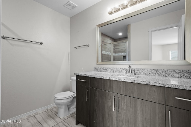 bathroom featuring vanity, baseboards, visible vents, a shower stall, and toilet