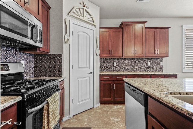 kitchen featuring light stone countertops, stainless steel appliances, and tasteful backsplash