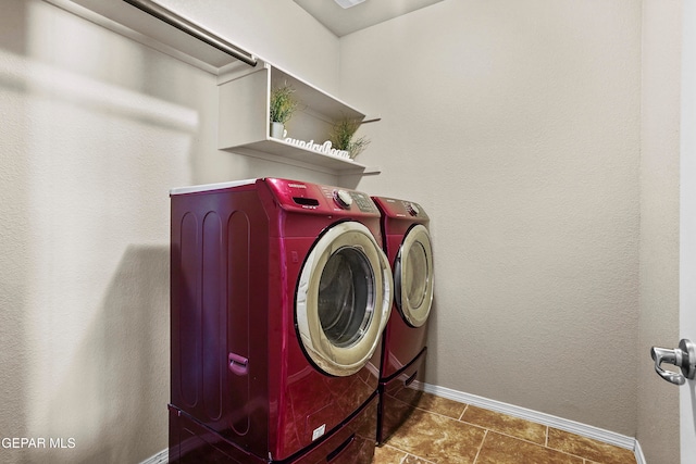 clothes washing area with dark tile patterned floors and washing machine and clothes dryer