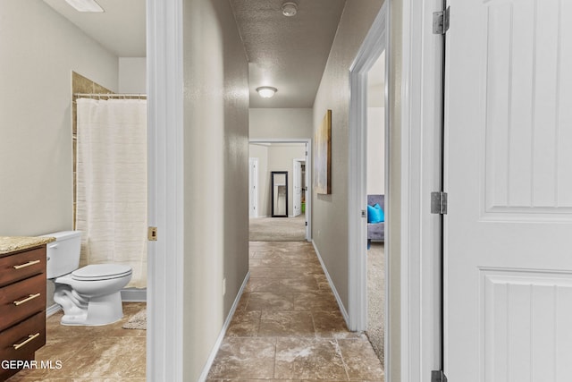 hallway with carpet flooring and a textured ceiling