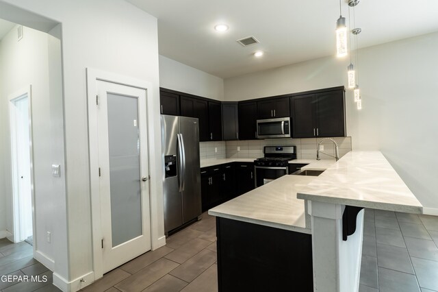 kitchen with decorative light fixtures, tasteful backsplash, a breakfast bar, stainless steel appliances, and kitchen peninsula