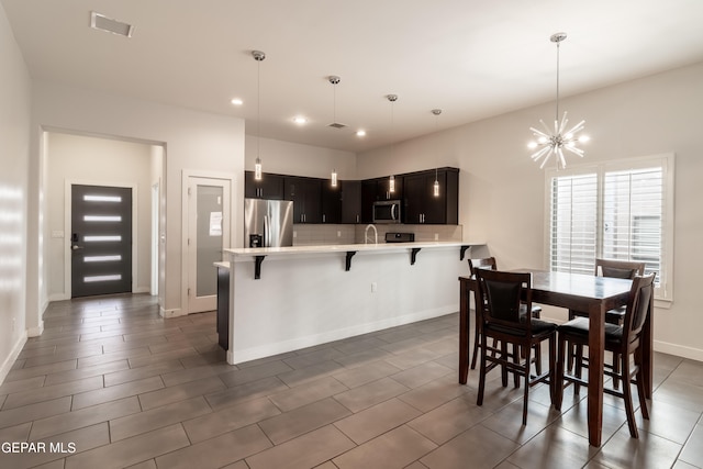 kitchen featuring hanging light fixtures, stainless steel appliances, a notable chandelier, kitchen peninsula, and a breakfast bar