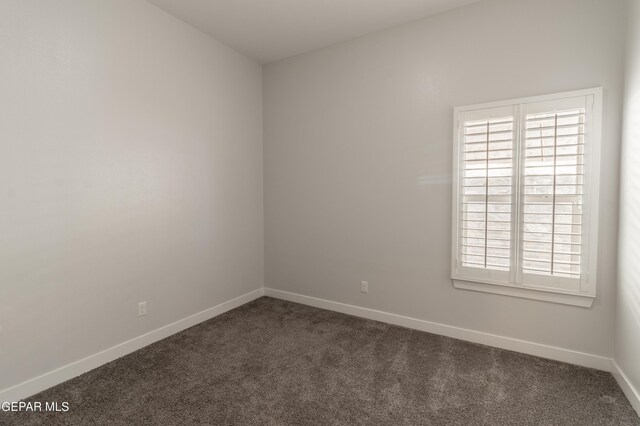 spare room with dark colored carpet and a healthy amount of sunlight