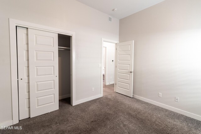 unfurnished bedroom with a closet and dark colored carpet