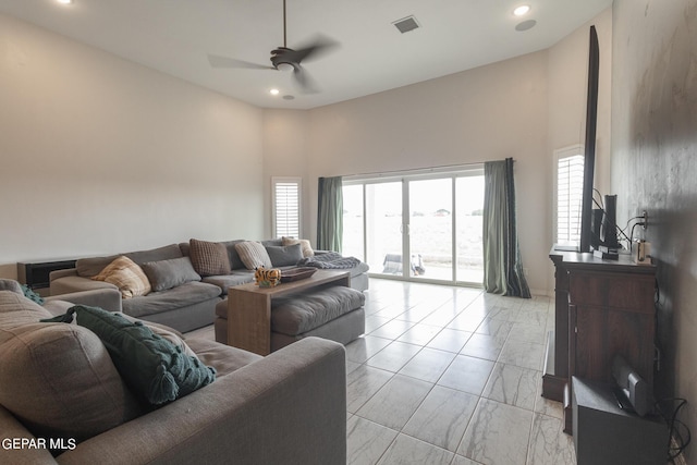 living area featuring a ceiling fan, visible vents, recessed lighting, a towering ceiling, and marble finish floor