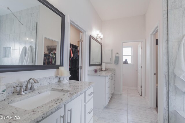 bathroom with tiled shower and vanity