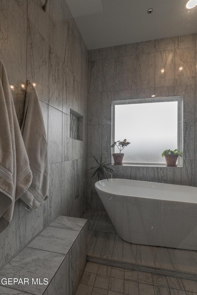 bathroom featuring a bath and tile walls