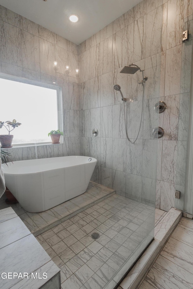 bathroom with a soaking tub, tile walls, marble finish floor, and tiled shower