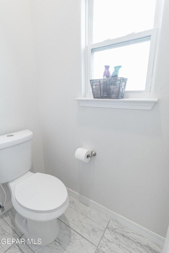 bathroom featuring marble finish floor, toilet, and baseboards