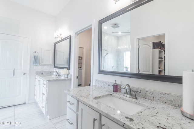 bathroom featuring a sink, two vanities, a spacious closet, and a shower stall
