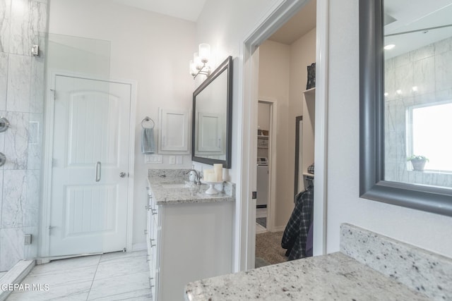 bathroom featuring a spacious closet, a shower stall, and vanity