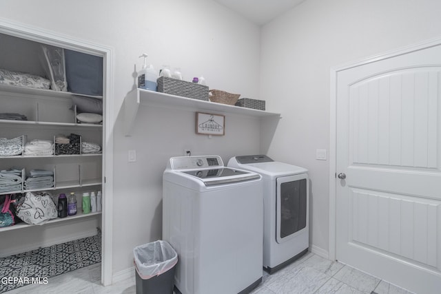 washroom featuring laundry area, marble finish floor, baseboards, and separate washer and dryer