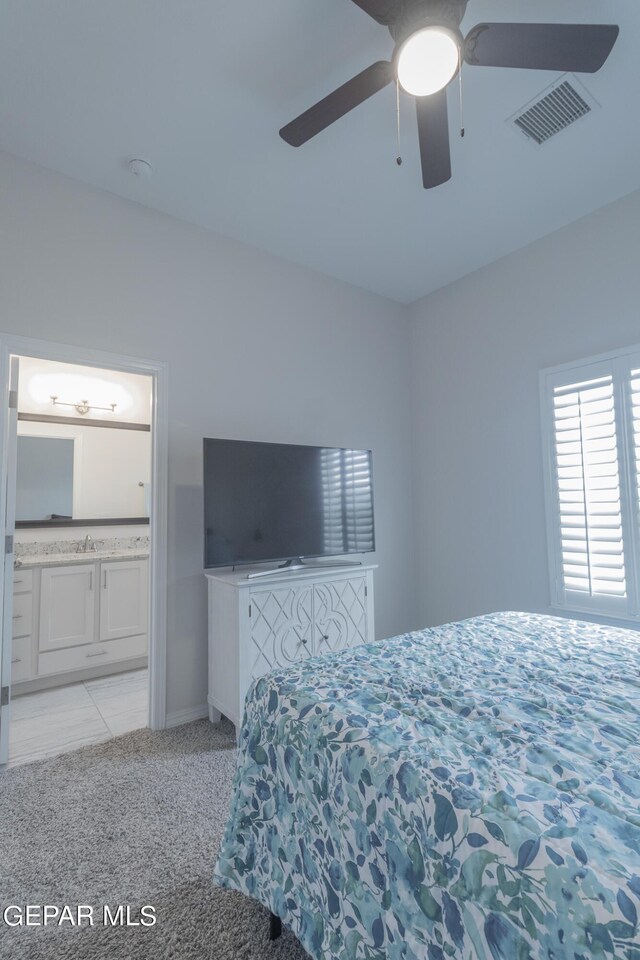 carpeted bedroom with ceiling fan, sink, and ensuite bath