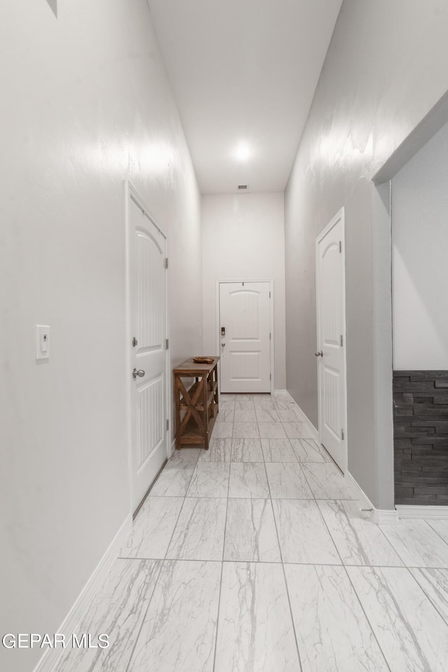 hallway with visible vents, marble finish floor, and baseboards