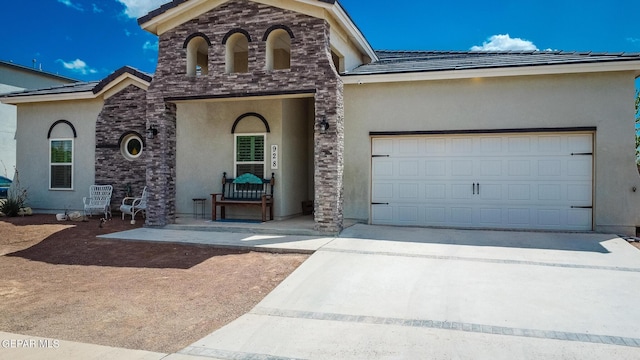 view of front facade with stucco siding, driveway, a tile roof, and a garage