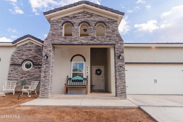 entrance to property featuring concrete driveway, a garage, and stucco siding