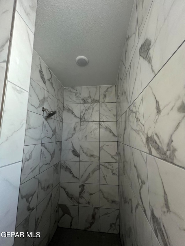 bathroom with a tile shower and a textured ceiling