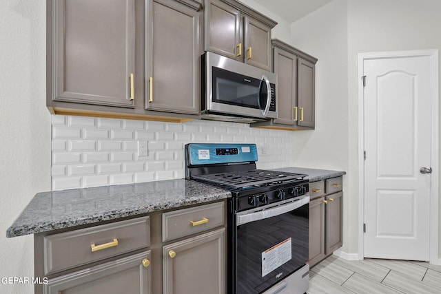 kitchen with stainless steel appliances, light hardwood / wood-style floors, stone countertops, gray cabinets, and tasteful backsplash