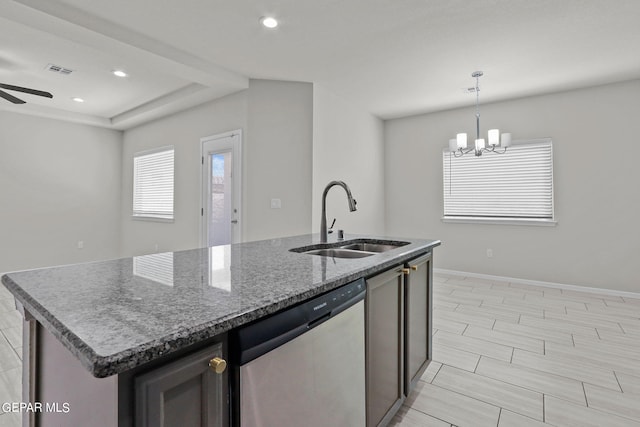 kitchen featuring ceiling fan with notable chandelier, an island with sink, stainless steel dishwasher, and sink