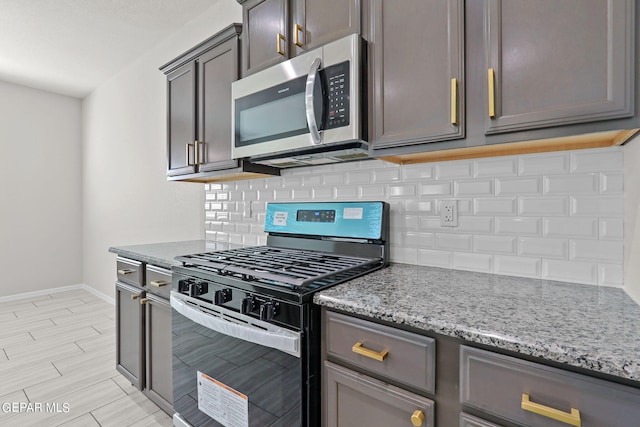 kitchen featuring black gas range oven, light stone counters, backsplash, and light hardwood / wood-style floors