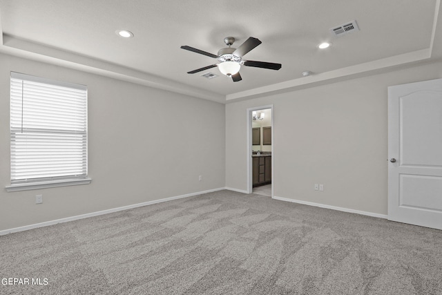 unfurnished room with ceiling fan, light colored carpet, and a raised ceiling