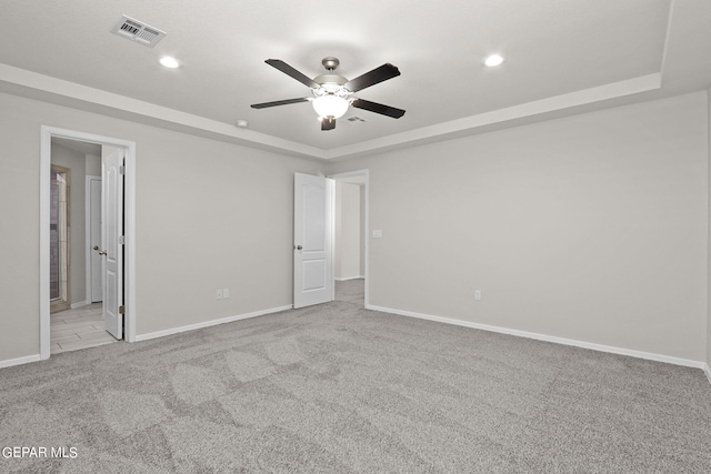 unfurnished bedroom with ceiling fan, a raised ceiling, and light carpet