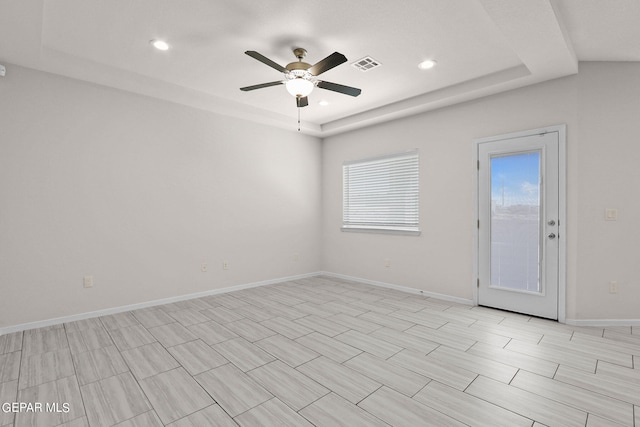 empty room featuring a tray ceiling and ceiling fan