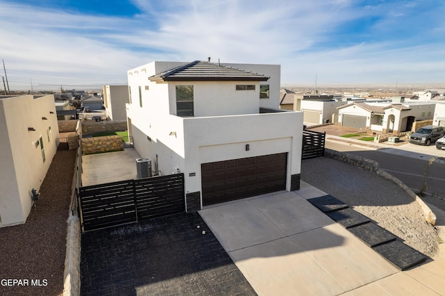 contemporary house with stucco siding, cooling unit, concrete driveway, and fence