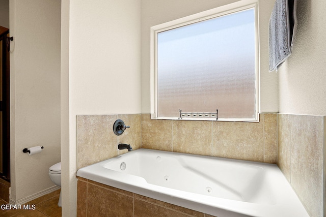 bathroom featuring plenty of natural light, toilet, and tiled tub