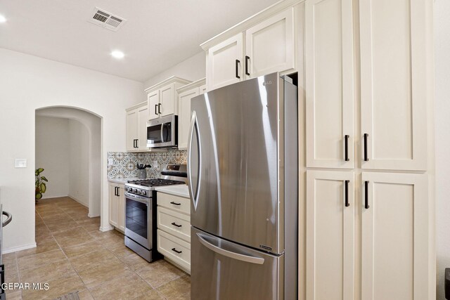 kitchen with stainless steel appliances, white cabinets, and tasteful backsplash