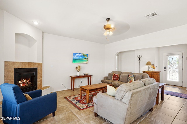 living room with ceiling fan, light tile patterned floors, and a tile fireplace