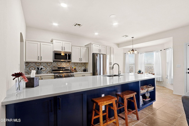 kitchen with a chandelier, stainless steel appliances, sink, hanging light fixtures, and white cabinets