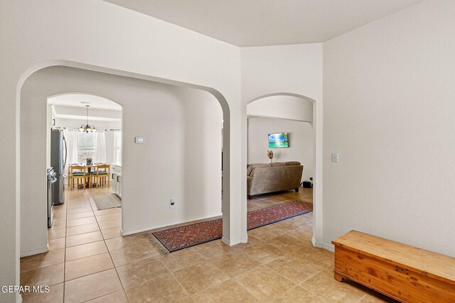 hall with a notable chandelier and light tile patterned flooring