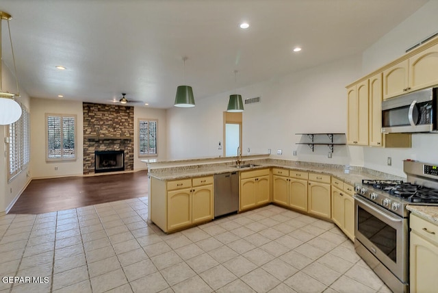 kitchen featuring sink, kitchen peninsula, decorative light fixtures, appliances with stainless steel finishes, and light hardwood / wood-style floors