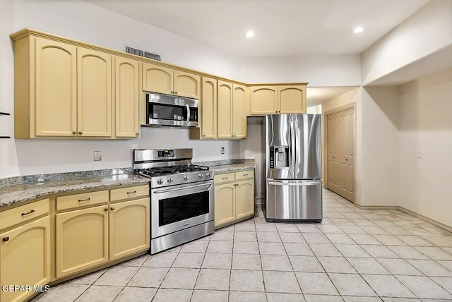 kitchen featuring stainless steel appliances, light tile patterned floors, and stone countertops