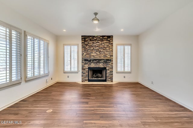 unfurnished living room featuring ceiling fan, a stone fireplace, and dark hardwood / wood-style floors